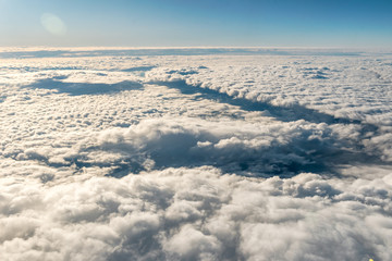 Traveling by air. View through an airplane window. Flying over cirrus and cumulus clouds with little turbulence, showing Earth's atmosphere.