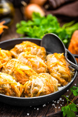 Cabbage rolls stewed with meat and vegetables in pan on dark wooden background