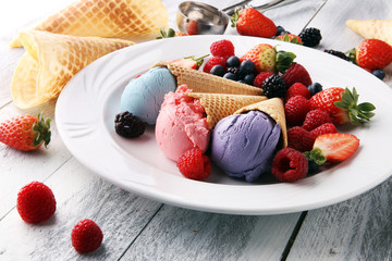 Set of ice cream scoops of different colors and flavours with blueberries, raspberries and blackberries.