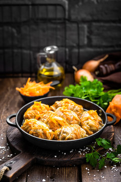 Cabbage rolls stewed with meat and vegetables in pan on dark wooden background