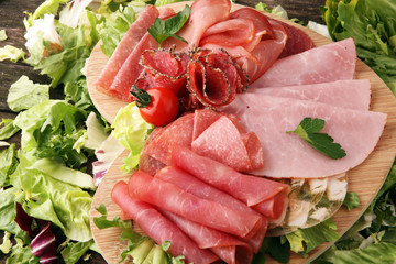 Food tray with delicious salami, pieces of sliced ham, sausage, tomatoes, salad and vegetable - Meat platter with selection