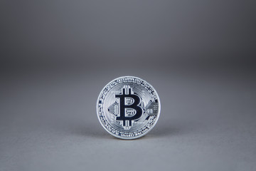 Silver bitcoin on a gray background front view