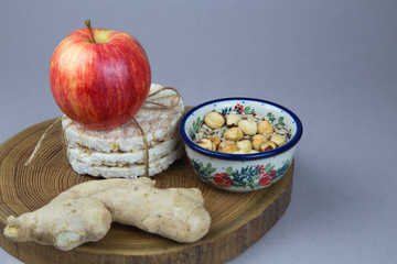 Apple, rice cake, ginger, sunflower seeds and hazel nuts on a wooden slice