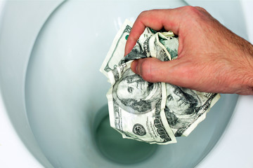 Flush money down the toilet, throws dollar bills in the toilet, loss concept, close up, selective focus