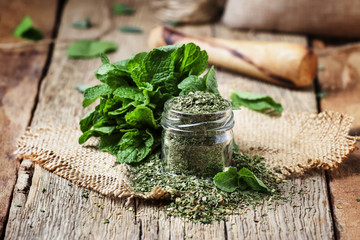 Dried peppermint in a glass jar and a bunch of fresh mint, vintage wood background, selective focus - obrazy, fototapety, plakaty