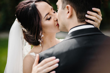 Confident elegant groom and beautiful shy bride holding hands ou