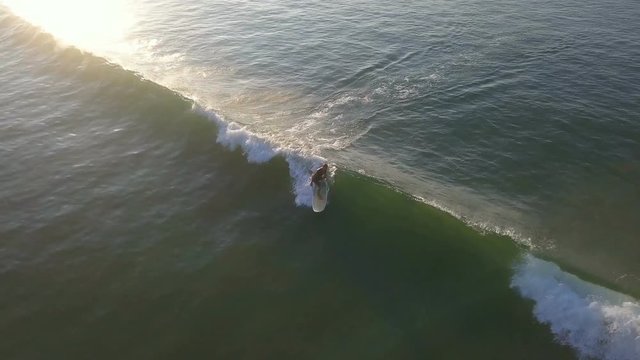 Stunning aerial drone shot of surfer catching wave sunrise footage