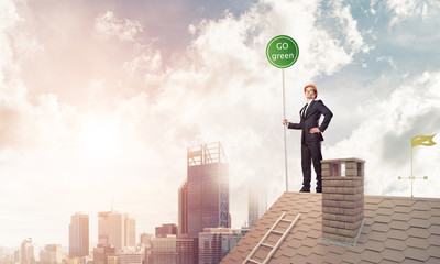 Businessman in suit on house top with ecology concept signboard.