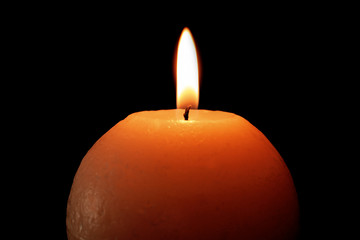 Burning candle on black background, closeup