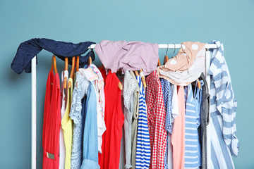 Rack with different clothes near color wall