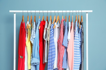 Rack with different clothes near color wall