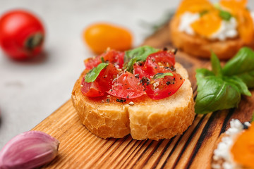 Tasty bruschetta with tomatoes on wooden board, closeup