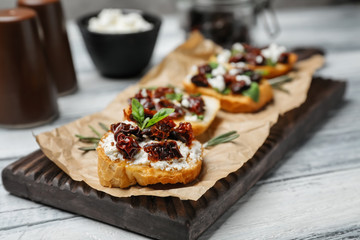 Tasty bruschettas with sun-dried tomatoes on wooden board, closeup