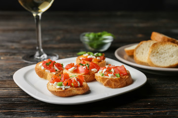 Tasty bruschettas with tomatoes on plate, closeup