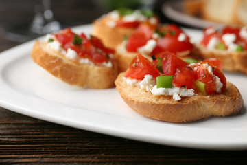 Tasty bruschettas with tomatoes on plate, closeup