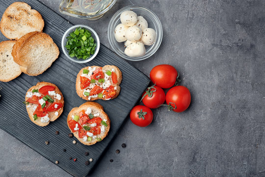 Tasty bruschettas with tomatoes on wooden board, top view