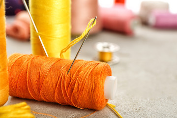 Spool of sewing thread with needle on table