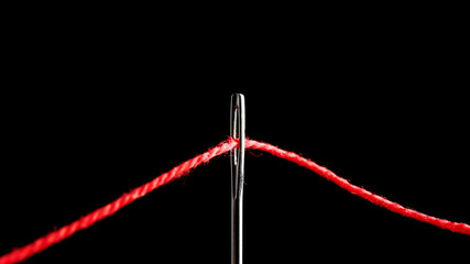 Needle with sewing thread on black background, closeup