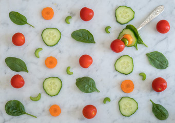 Pattern of Salad Ingredients on Marble Bench Top, Baby Spinach Leaves, Carrot, Cherry Tomatoes, Celery and Cucumber with a Combination of them on a Fork