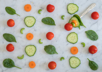 Fototapeta na wymiar Pattern of Salad Ingredients on Marble Bench Top, Baby Spinach Leaves, Carrot, Cherry Tomatoes, Celery and Cucumber with a Combination of them on a Fork