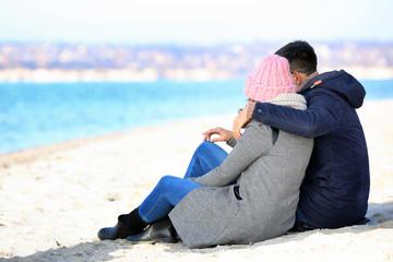 Happy loving young couple sitting on river bank