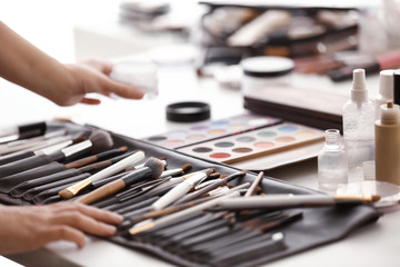 Professional visage artist with makeup accessories at workplace