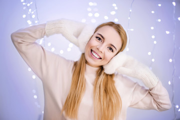 Happy woman in earmuffs against blurred lights