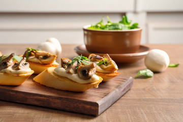 Tasty bruschettas with mushrooms on wooden board