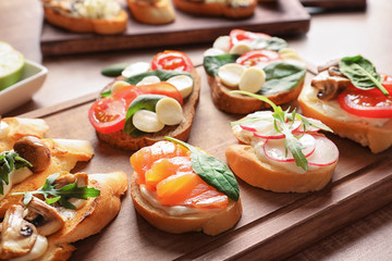 Tasty bruschettas on wooden board, closeup