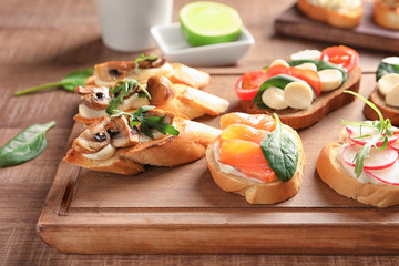 Tasty bruschettas on wooden board, closeup
