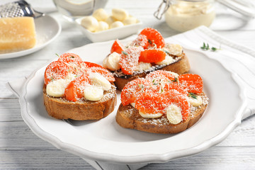 Tasty bruschettas with cherry tomatoes and cheese on plate, closeup