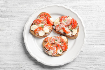 Tasty bruschettas with cherry tomatoes and cheese on plate