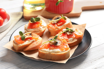 Tasty bruschettas with salmon on plate, closeup