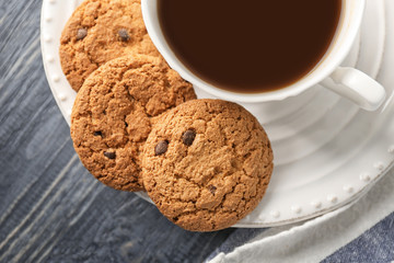 Delicious oatmeal cookies with chocolate chips and cup of coffee on plate