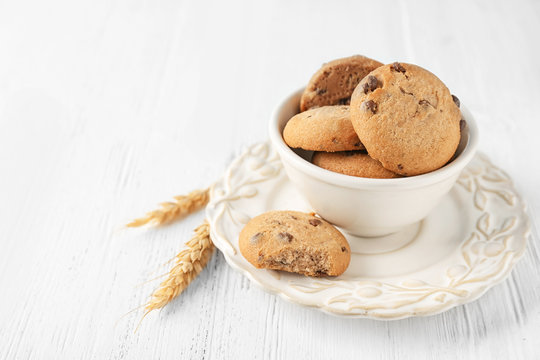 Delicious oatmeal cookies with chocolate chips in bowl on table