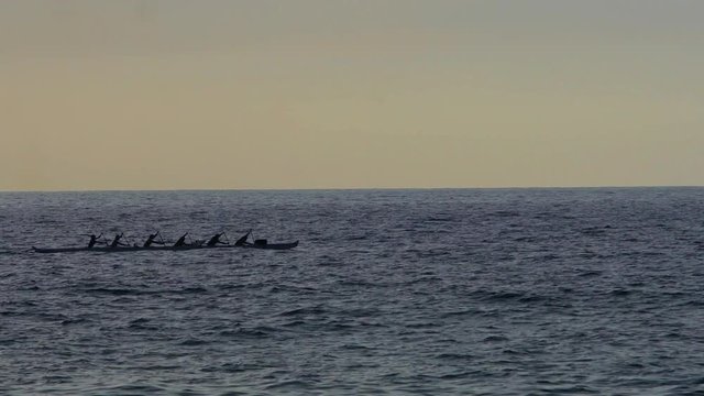 A rowing team on an outrigger canoe on the open sea