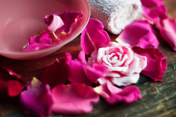 Bowl with water and rose petals on wooden table