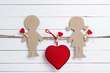 Cardboard silhouettes girl and boy with heart on white wooden background. Space for text.