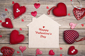 Greeting Valentines Day card with home symbol and red hearts on wooden background.