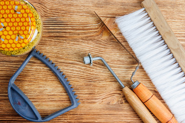 Fresh honey in the comb and the tools of the beekeeper on a brawn vooden background. Flat lay and top view