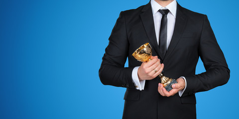 Unrecognizable businessman with a golden trophy. Success concept