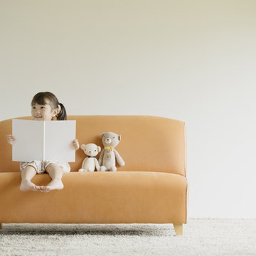ソファーに座り絵本を読む女の子