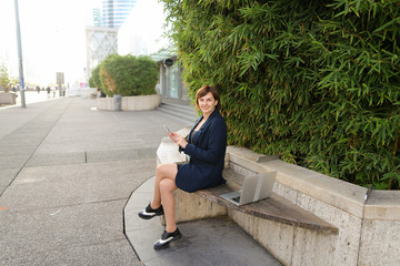 Businesswoman typing message and listening to music outside with