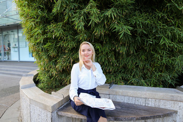 Lady reading newspaper outdoors in   with close up face.