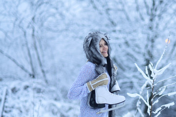 Girl happy smile with figure skates at trees in snow