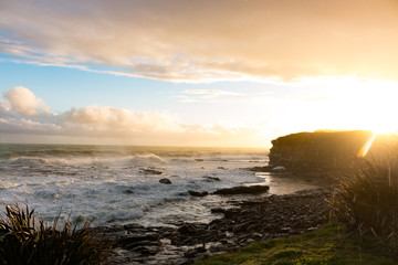 New Zealand Curio Bay south island rough coastline shore with waves and cliffs at sunset