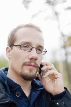 Headshot ofÂ young man talking on phone outdoors