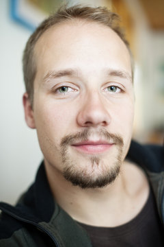 Headshot portrait of young man with moustache and beard