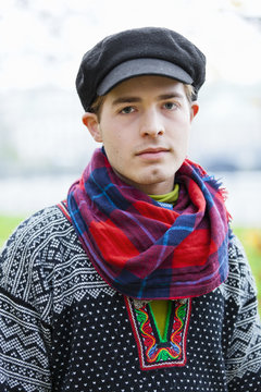 Portrait of young man in flat cap and checked scarf looking at camera