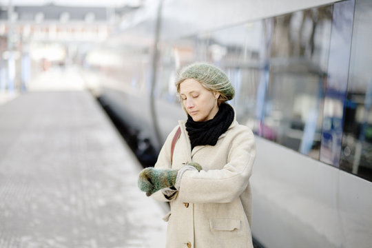 Adult woman checking time&Acirc;&nbsp;beside train waiting at train station